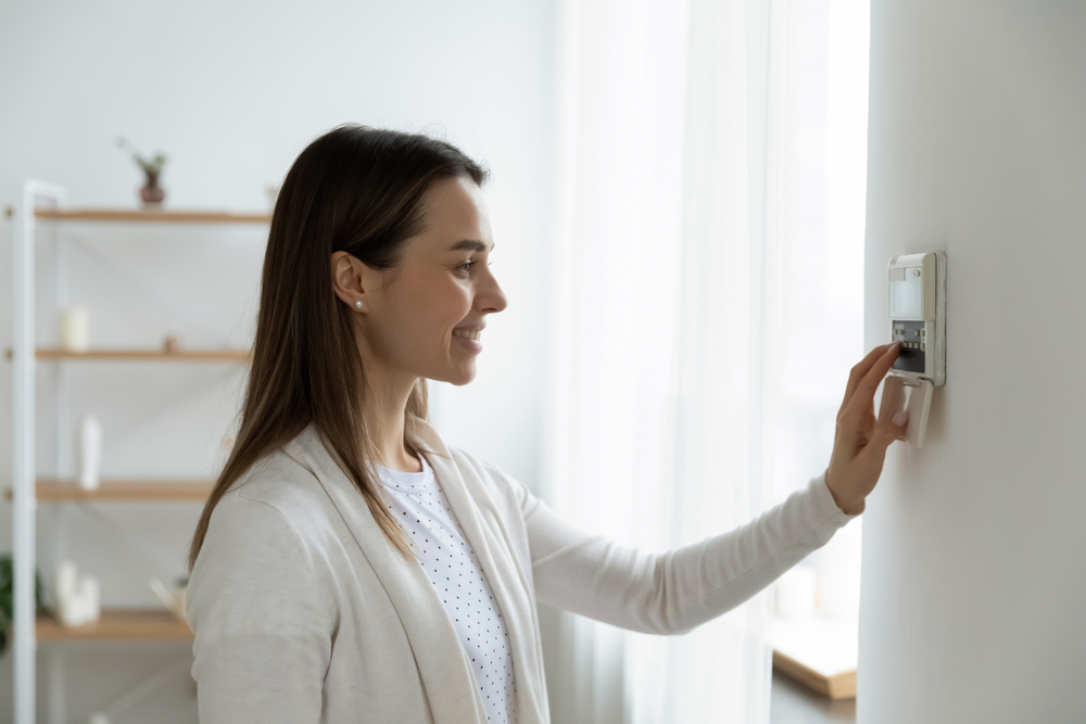 Une femme réglant le thermostat pour faire des économies de chauffage en hiver
