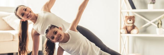 Jeune femme et sa petite fille font du yoga ensemble à la maison
