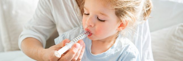 Un enfant reçoit une dose de médicament liquide administrée avec une seringue orale.