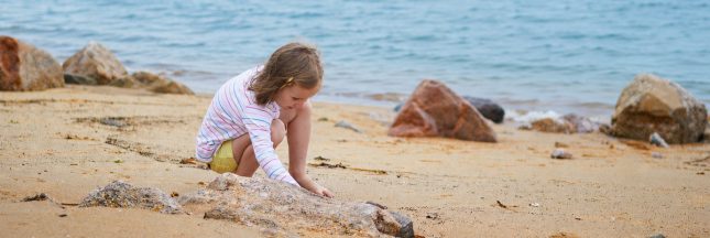 Fillette jouant sur une plage avec la mer en arrière-plan