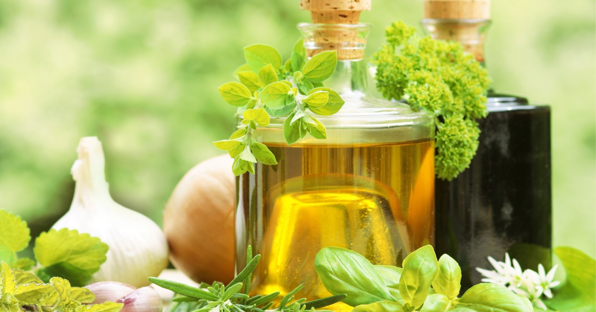 Bouteille en verre propre contenant du vinaigre de cidre infusé aux fleurs de basilic et herbes fraîches du jardin.