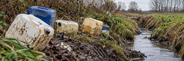 Bidons abandonnés au bord d’un cours d’eau, illustration de la pollution liée aux déchets chimiques clandestins.